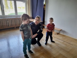 policjantka przykuca między dwoma przedszkolakami