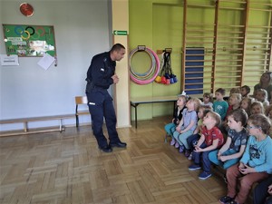 policjant rozmawia z grupą dzieci, scena ma miejsc w sali