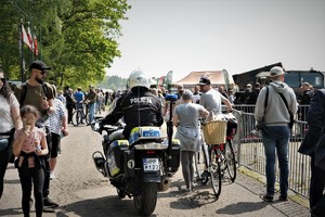 policjant ruchu drogowego na motocyklu przejeżdża wśród tłumu ludzi