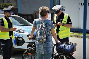 policjanci drogówki rozmawiają z kobietą, która porusza się na rowerze