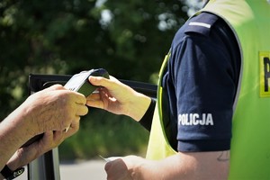 policjant drogówki trzyma w ręce terminal płatniczy