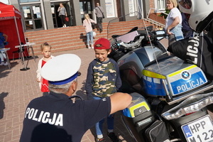 policjant drogówki oparty o motocykl rozmawia z małym dzieckiem