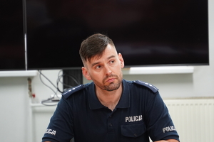 siedzący przy stoli policjant w stopniu aspiranta