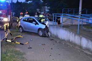 samochód marki fiat, który uderzył w mur budynku, wokół ludzie, w tym służby drogowe i policjanci