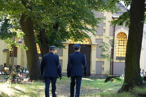 dwaj policjanci w mundurach wyjściowych opuszczają teren cmentarza