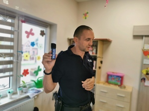 policjant prezentuje dzieciom policyjny gaz