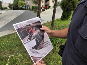 policjant trzyma w ręku ulotkę kampanii społecznej „Bezpieczny sk8park &amp; pumptrack”