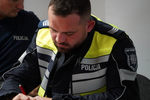 policjant katowickiej drogówki notuje zapiski z prowadzonej odprawy do zabezpieczenia wyścigu