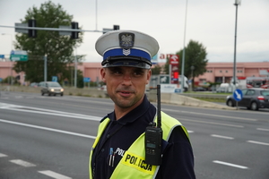 policjant drogówki Jakub Goliasz stoi na skrzyżowaniu, w tle centrum handlowe Auchan w Mikołowie