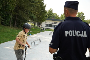 policjant rozmawia z chłopcem jeżdżącym na hulajnodze