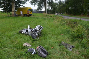 leżące na poboczu fragmenty rozbitego motocykla, w oddali żółty bus