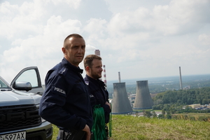 dwaj umundurowani policjanci na łaziskie hałdzie, w tle kominy elektrowni