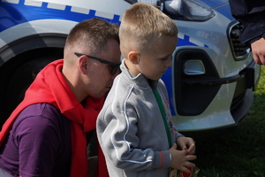 mały chłopiec ze swoim tatą, za nimi policyjny radiowóz