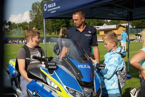 policjant prezentuje dzieciom oznakowany motocykl
