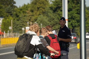 policjant rozmawia na chodniku z uczniami szkoły