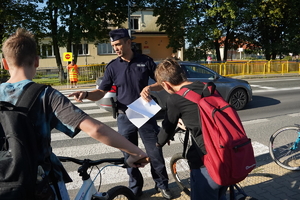 uczniowie oraz policjant przechodzą przez oznakowane przejście dla pieszych