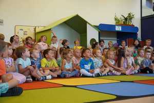 grupa przedszkolaków siedzi na kolorowym dywanie