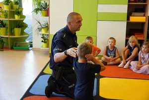 policjant wraz z małym chłopcem pokazuje dzieciom sposób zachowania w razie ataku psa