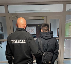 policjant wydziału kryminalnego wyprowadza zatrzymanego z komendy