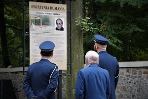 dwaj policjanci i mężczyzna pod tablicą informacyjną