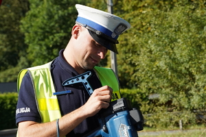 policjant drogówki przegląda zapis ręcznego miernika prędkości