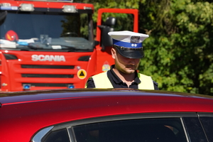 policjant drogówki podczas kontroli samochodu koloru bordowego