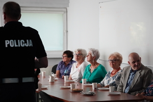 policjant w trakcie wykładu z seniorami. Scena ma miejscu na auli jednostki