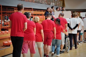 jedna z drużyn spartakiady, osoby idą jedna za drugą, mają na sobie czerwone koszulki