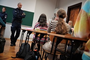 dwoje policjantów podczas spotkania profilaktycznego w liceum, uczniowie siedzą w ławkach