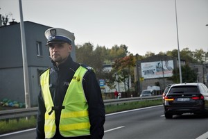 stojący przy trasie policjant drogówki w odblaskowej kamizelce