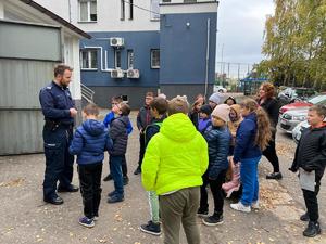 teren parkingu przy komisariacie. Dzieci zgromadzone wokół policjanta