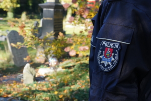 fragment policyjnego munduru,w tle groby