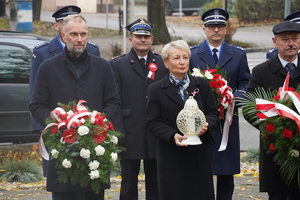 delegacja samorządowców i mundurowych, osoby niosą znicze i kwiaty