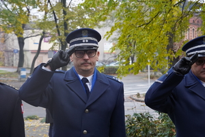 policjanci w mundurach wyjściowych salutują przed pomnikiem