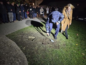 policjant przysypuje ziemią zakopaną kapsułę