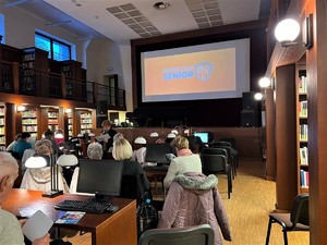 sala w bibliotece, seniorzy siedzą na krzesłach