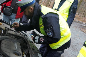 policjant zagląda pod maskę auta