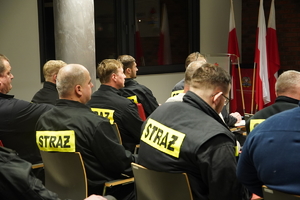 siedzący na krzesłach w sali szkoleniowej strażacy ochotnicy
