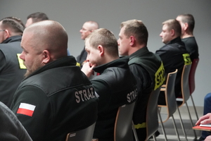strażacy ochotnicy siedzą na krzesłach w sali szkoleniowej