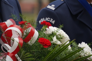 biało-czerwone kwiaty, w tle policyjny galowy mundur
