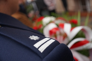 pagon na mundurze: podinspektor Policji, w tle biało-czerwone kwiaty