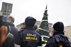 dwaj strażnicy miejscy podczas zbiórki, w tle ogromna choinka w centrum miasta