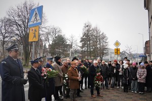 uroczysta zbiórka pod tablicą przy urzędzie miasta w Łaziskach Górnych. Ludzie stoją obok siebie