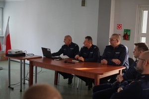 zdjęcie przedstawia  trzech policjantów siedzących przy stole