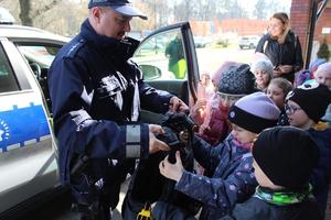 na zdjęciu widać policjanta trzymającego kamizelkę i dzieci