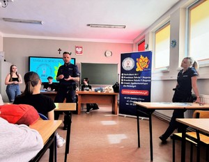 na zdjeciu widać policjanta i uczniów w klasie