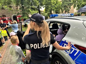 na zdjeciu widać policjantkę, radiowóz i dzieci