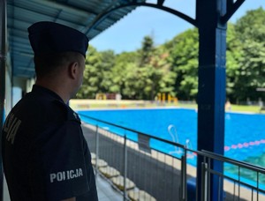 na zdjeciu widać policjanta i basen