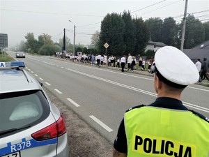 na zdjeciu widać policjanta i radiowóz przy szkole