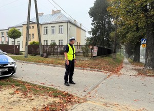 na zdjeciu widać policjanta i radiowóz przy szkole